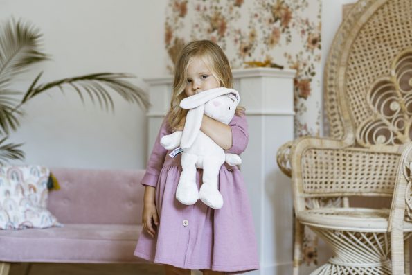 dziewczynka stoi i przytula szumiącego króliczka Whisbear