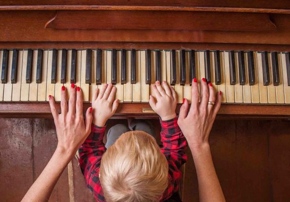 mama z niemowlakiem grają na pianinie na cztery ręce